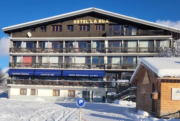 Un hotel de varios pisos con balcones, una pizzería y un restaurante.