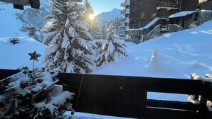 Paisaje nevado con un edificio y un árbol de Navidad al frente.