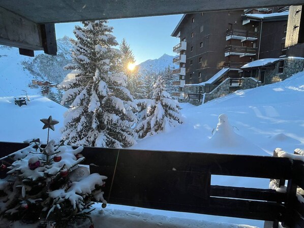 A snow-covered landscape with a building and a Christmas tree in the foreground.
