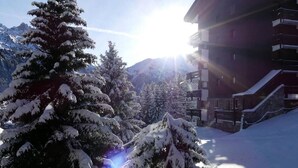 Un paisaje montañoso cubierto de nieve con un edificio que tiene varios balcones y una escalera que lo conduce.