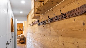 Un pasillo con paneles de madera, un perchero y una puerta que da a una habitación con sofá y chimenea.