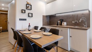 Una cocina moderna con armarios blancos, una mesa de comedor de madera, sillas negras y un horno empotrado.