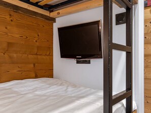 Ein Schlafzimmer mit einem Bett, einem an der Wand befestigten Fernseher und Holzvertäfelung.