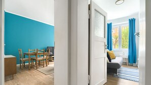 A room with a dining area, a sofa, and a view of the outside.