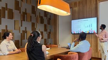 A conference room with a wooden table, leather chairs, and a presentation screen displaying a product overview.
