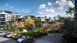 A modern residential complex with multiple two-story buildings, a parking area with several cars, and lush greenery including palm trees and flowering plants. - Royal Green (Moka)