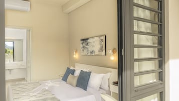 A bedroom with a bed, a window, a wall-mounted light, and a painting.