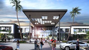A modern building with a covered entrance, palm trees, and people walking around.
