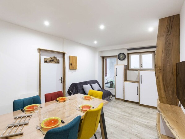 Uma sala de jantar com uma mesa de madeira posta para quatro pessoas, rodeada por cadeiras azuis e amarelas.
