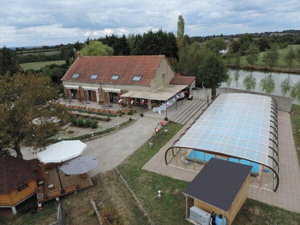 A building with a tiled roof, a covered outdoor area, and a swimming pool.