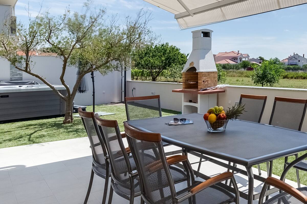 An outdoor patio with a table, chairs, and a fruit bowl.