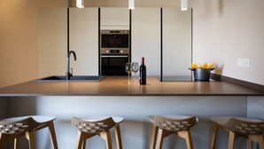 Eine moderne Küche mit Kochinsel, Barhocker, Spüle und Backofen.