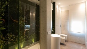 Ein modernes Badezimmer mit einer Duschkabine, die Wasserpflanzen beherbergt, einem weißen Waschbecken und zwei Toiletten.