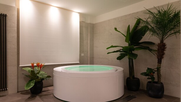 Ein modernes Badezimmer mit einer zentralen Whirlwanne, einem Heizkörper und Topfpflanzen.
