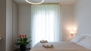 Ein Hotelzimmer mit Bett, Topfpflanze und einem Vorhangfenster.