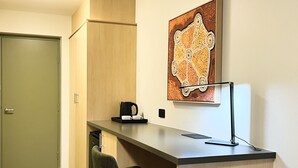 Une petite cuisine équipée d’une machine à café, d’une chaise et d’un tableau accroché au mur.