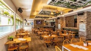 Un restaurant avec des tables et des chaises en bois, des murs en briques et des plantes suspendues.