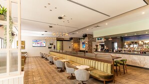 Un espace de détente moderne avec un long banc, des sièges rembourrés et un comptoir de bar.