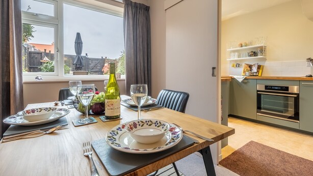 En matplats med ett bord dukat för två personer, en flaska vin och en skål med frukt.