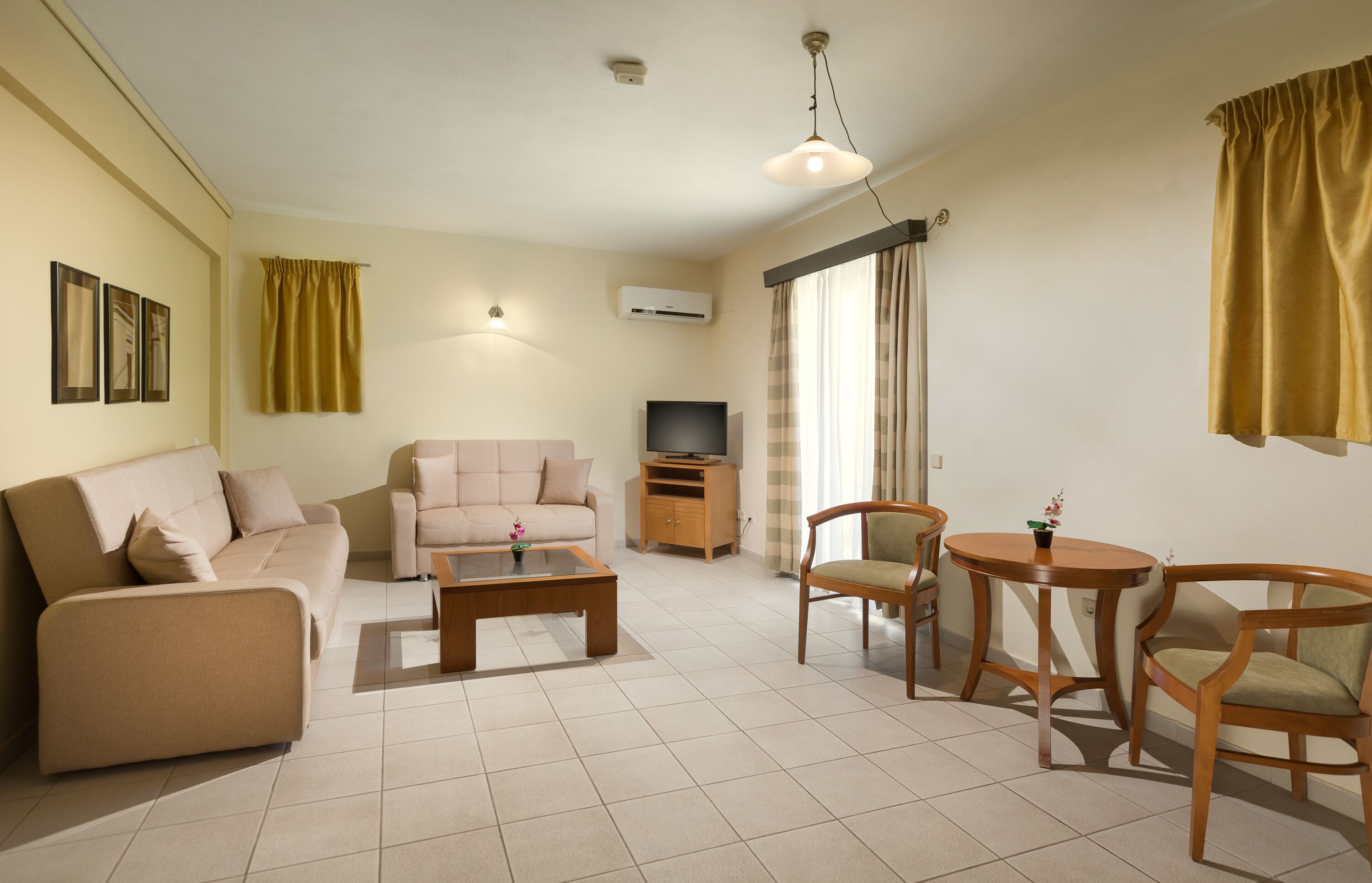 A living room with a sofa, a coffee table, two chairs, a TV, and a small table with a plant.