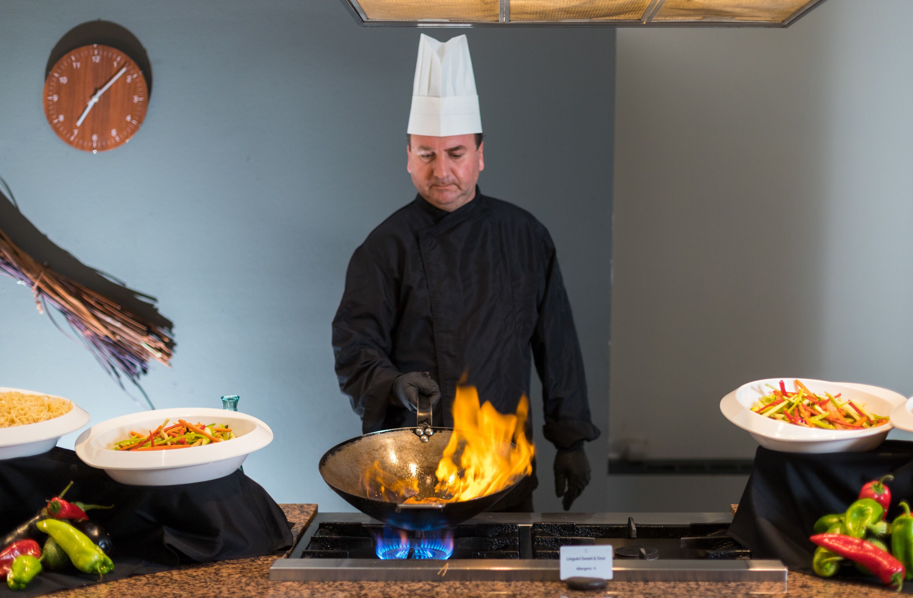 A chef cooking with a wok on a gas stove in a kitchen.