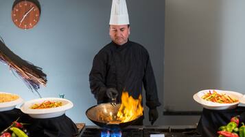 A chef cooking with a wok on a gas stove in a kitchen.