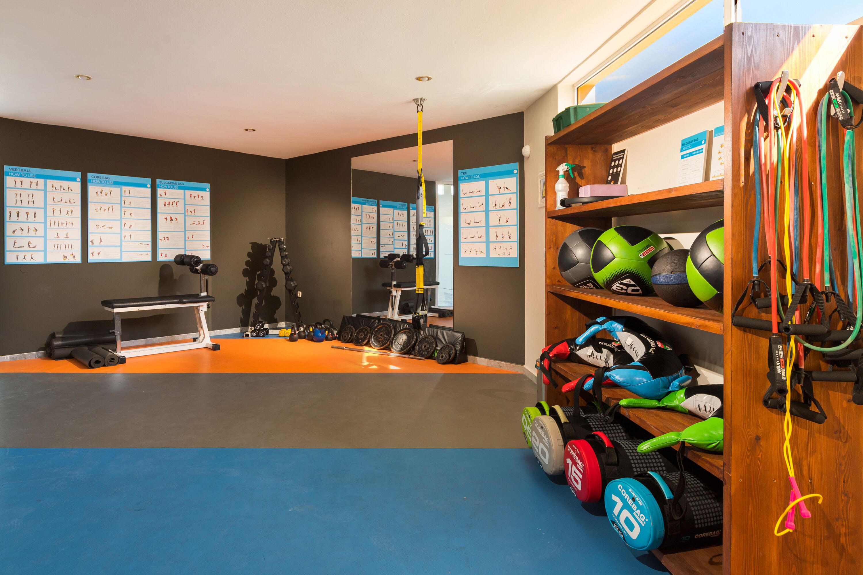 A gym with exercise equipment, a bench, and a wall with exercise charts.