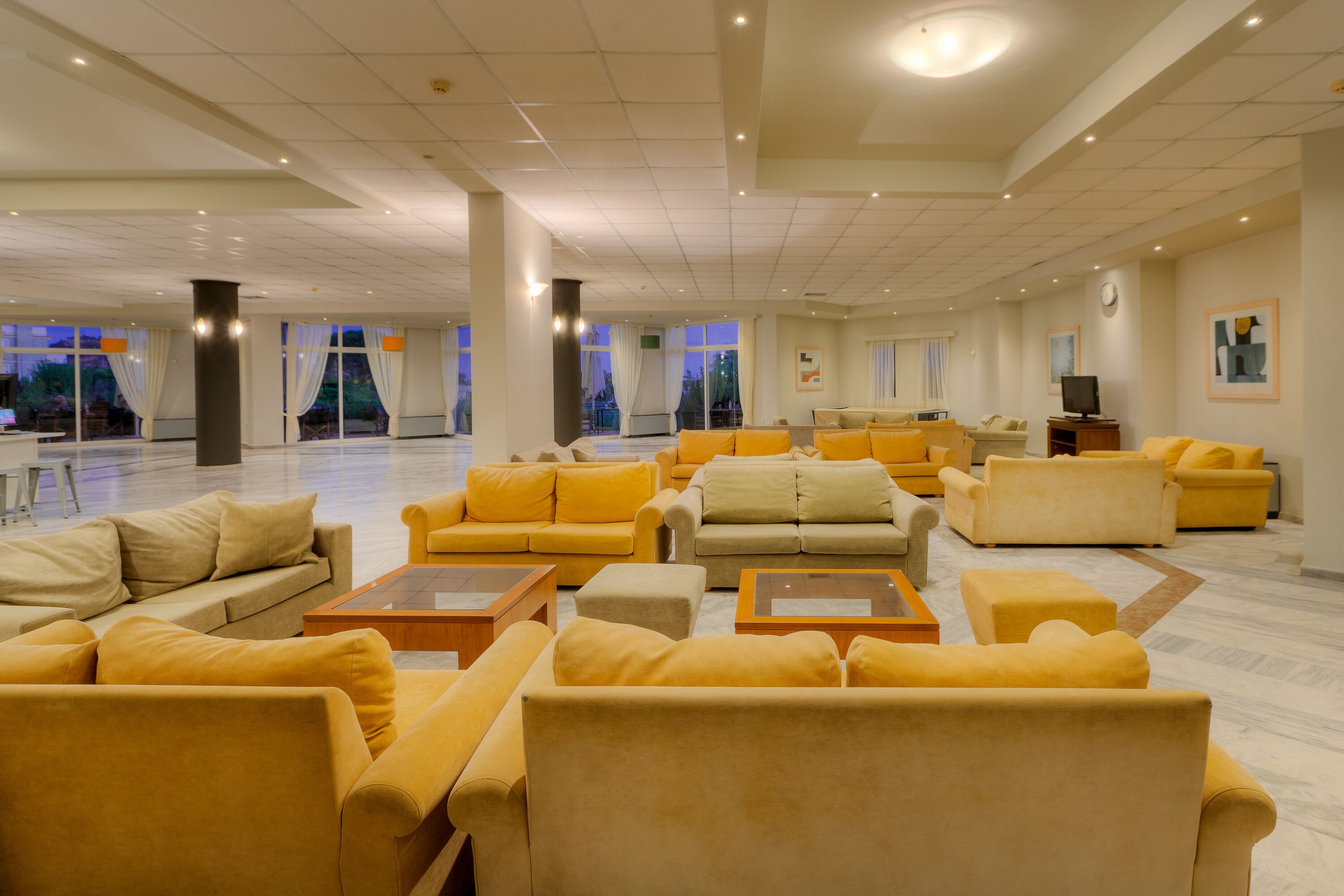A spacious living area with multiple yellow sofas and a television.