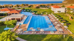 A resort with a large swimming pool, sun loungers, and a view of the sea. - Aeolian Village Beach Resort (Lesvos)