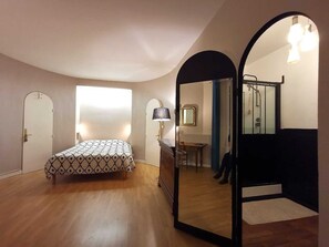 A bedroom with a bed, a dresser, a mirror, and a shower area.