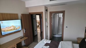 A hotel room with a bed, a TV, a minibar, and a shower area. - Hotel La SERA (Istanbul)