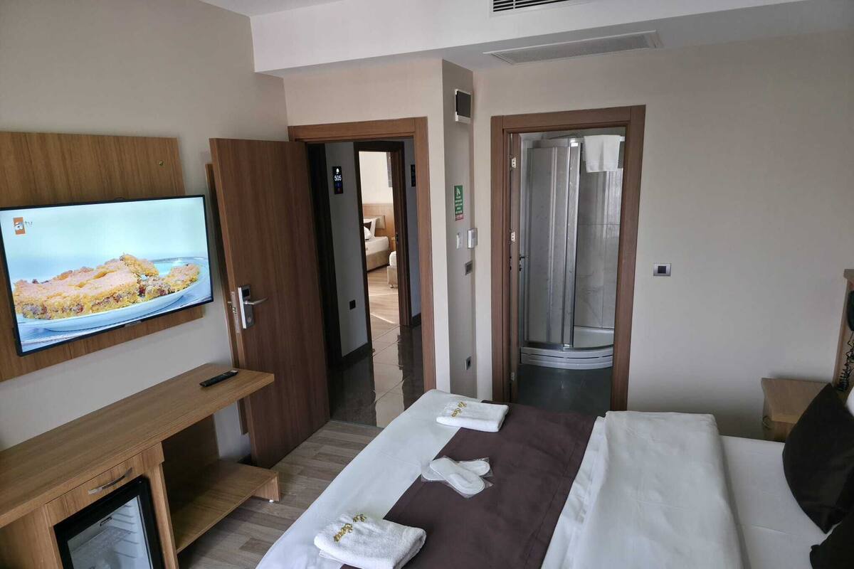 Ein Hotelzimmer mit Bett, Fernseher, Minibar und Duschbereich.