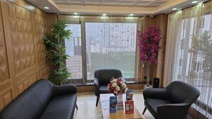 A modern reception area with two black leather sofas, a wooden coffee table with brochures, and a large window with sheer curtains. - Hotel La SERA (Istanbul)