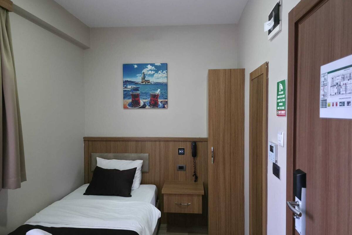 Ein Hotelzimmer mit einem Bett, einem Holzschrank, einem Telefon und einem Gemälde mit Meeresblick.