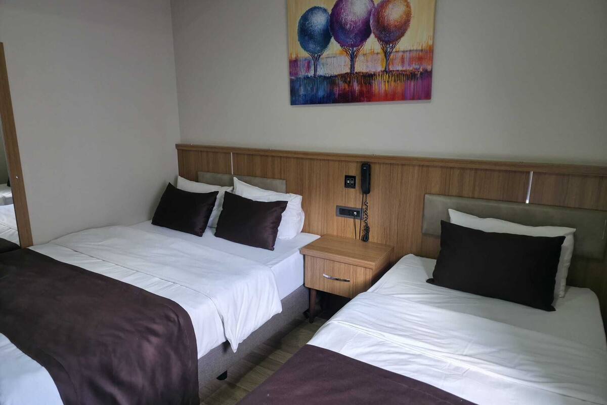 Ein Hotelzimmer mit zwei Betten, einem Holz-Kopfteil, einem Nachttisch mit Telefon und einem Bild an der Wand.