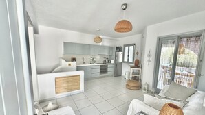 Zona d'estar i cuina moderna, oberta, amb sofà, taula de centre i taula de menjador.