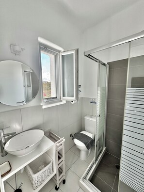 A modern bathroom with a toilet, sink, and shower. - A Perfect Home In Naxos (Stelida)
