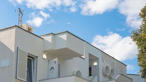A modern two-story house with a staircase leading to the upper floor, a small balcony, and a tree in the front yard. - Apartments Adela I (Novalja)