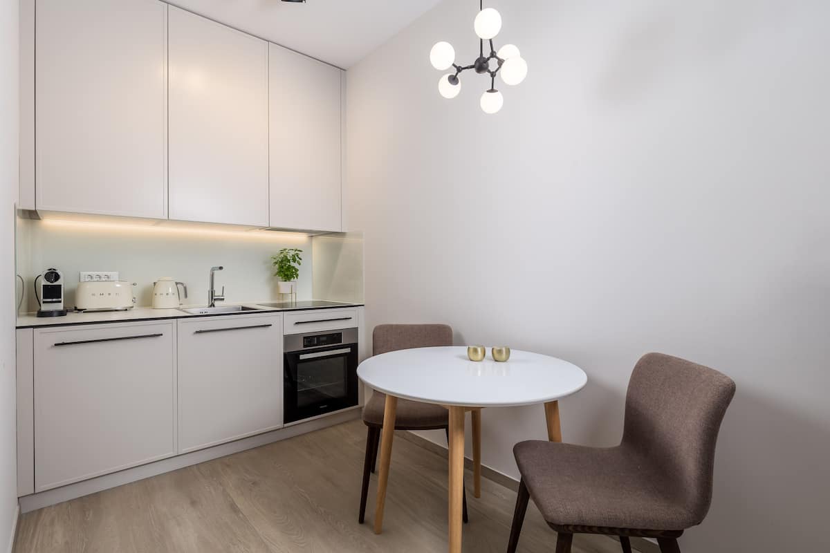A modern kitchen with white cabinets, a round dining table, and two chairs.