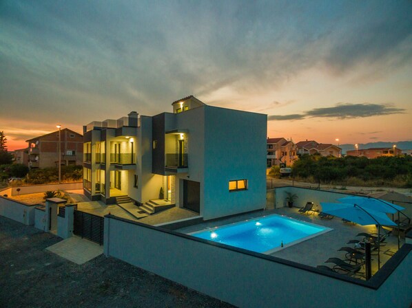 A modern two-story house with a swimming pool and outdoor seating.
