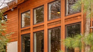 Una cabaña de madera con amplias ventanas y una campana en el tejado.