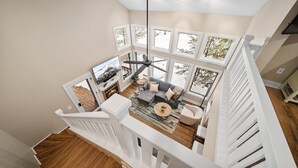 Un loft amplio con un ventanal grande, una chimenea y una escalera moderna.