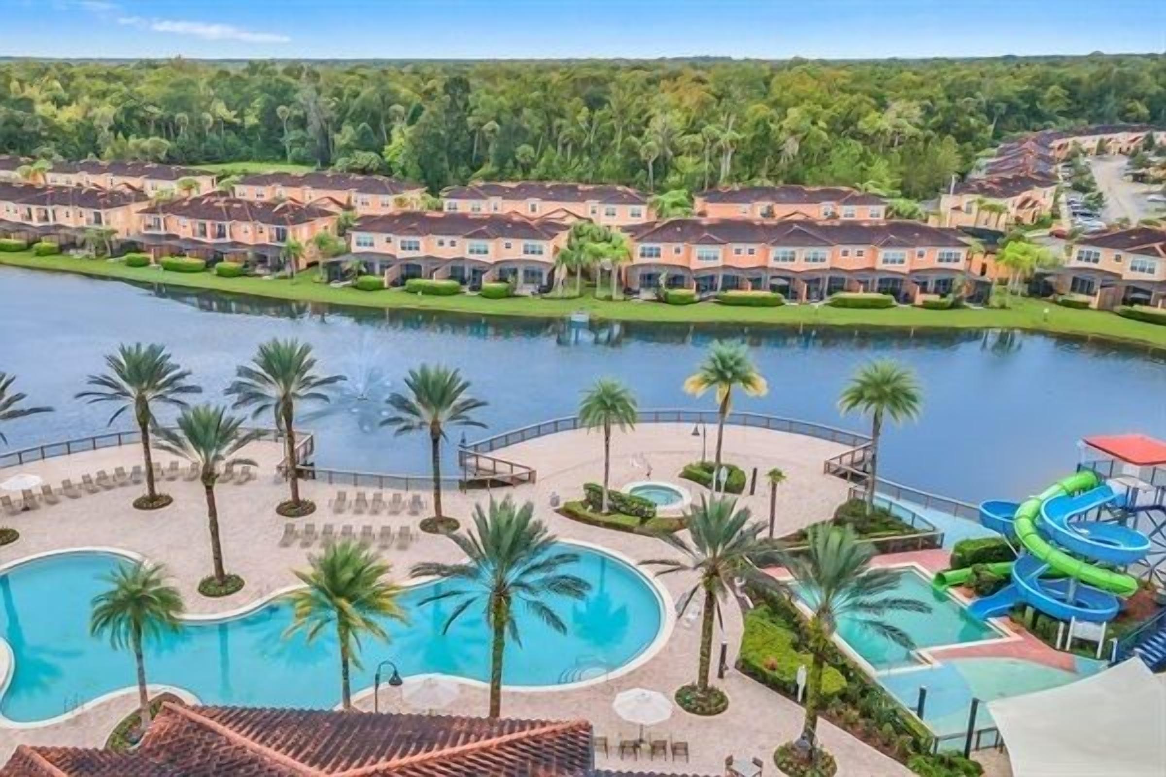 A resort with a large swimming pool, palm trees, and a water slide.
