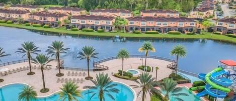 A resort with a large swimming pool, palm trees, and a water slide.