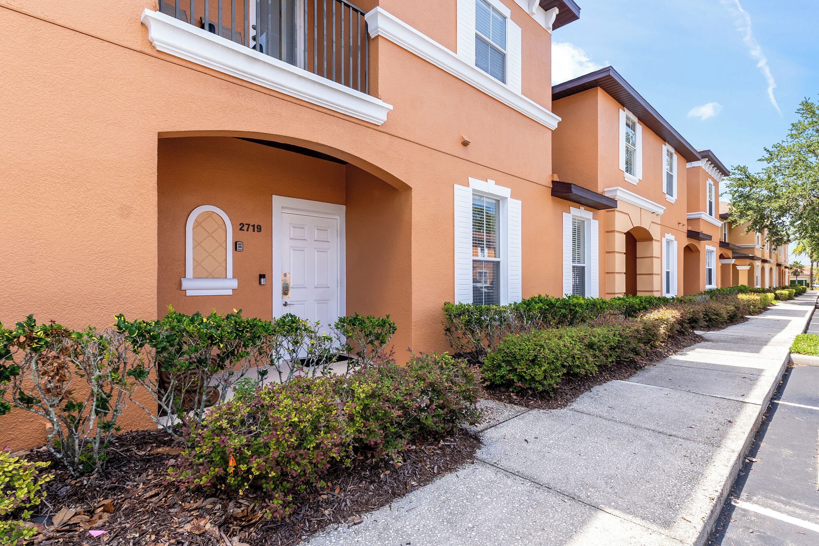 A row of townhouses with a white door, a mailbox, and a small garden area.