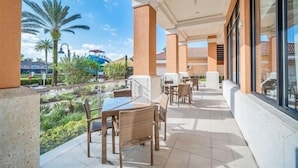 Un espace extérieur abrité, doté de tables et de chaises, d’où l’on peut admirer un paysage verdoyant et des bâtiments en arrière-plan.