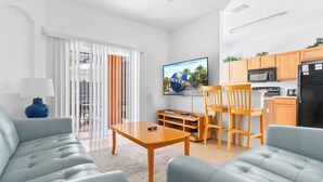 Un salon moderne avec un canapé, une table basse et un téléviseur.