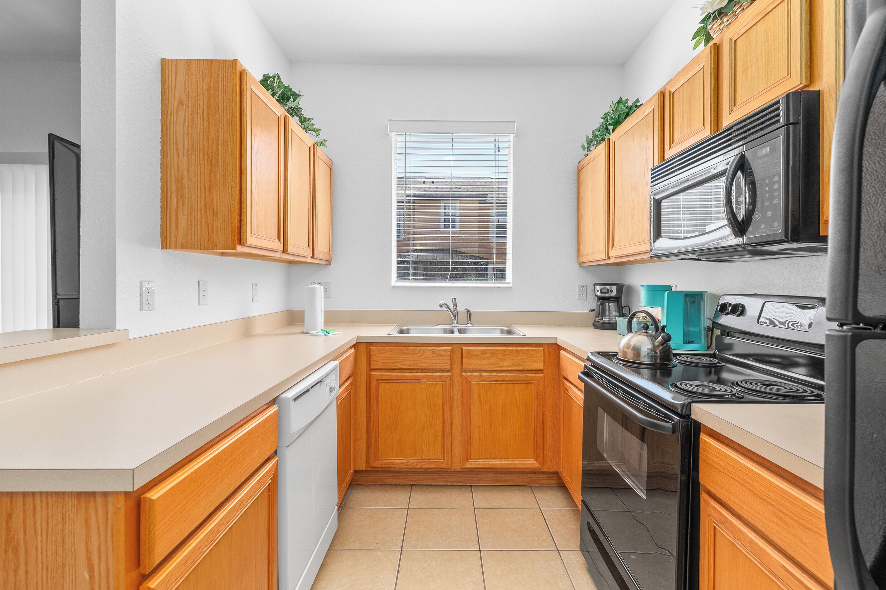 A kitchen with wooden cabinets, a stainless steel refrigerator, a stove, and a sink.