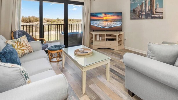 Ein Wohnzimmer mit einem Glastisch, zwei Sofas, einem Fernseher und einem Gemälde an der Wand.