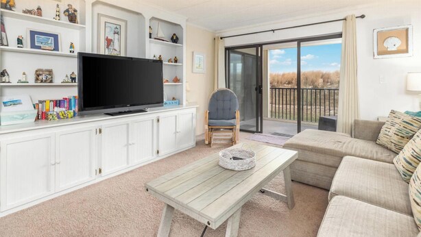 Una sala de estar con televisor, sofá, mesa y sillón.